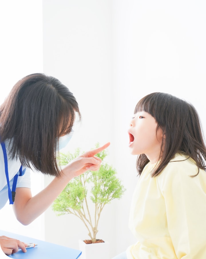 歯科医が子供の口の中を診て指さしている様子