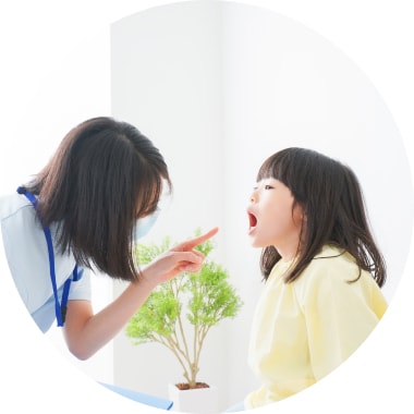 歯科医が子供の口の中を診ている様子